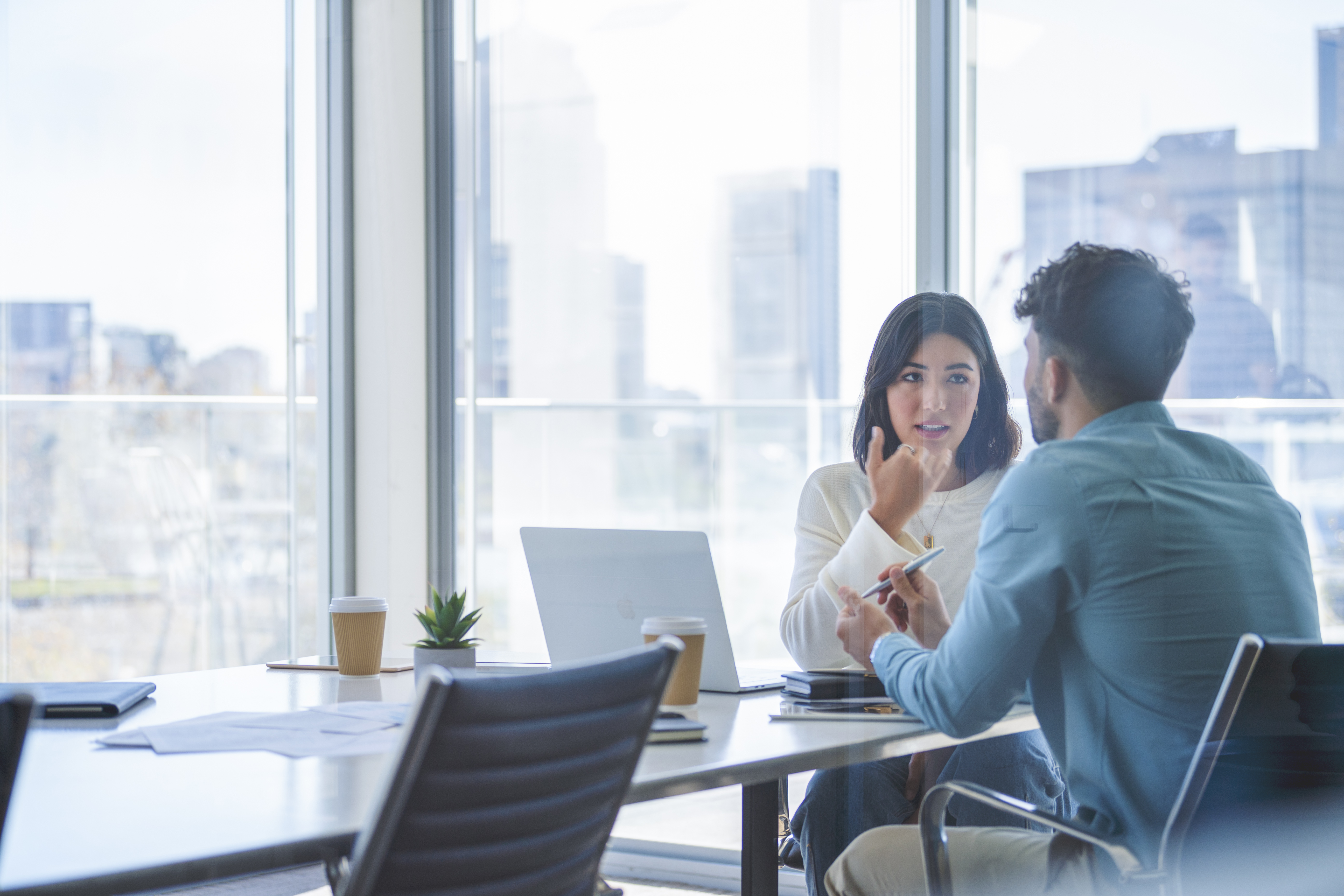 Two people sitting in a meeting room talking to each other rosen group